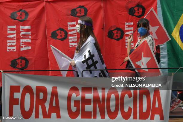 Demonstrator passes by a banner reading "Genocide out" during a protest against Brazilian President Jair Bolsonaro, in Sao Paulo, Brazil, on October...