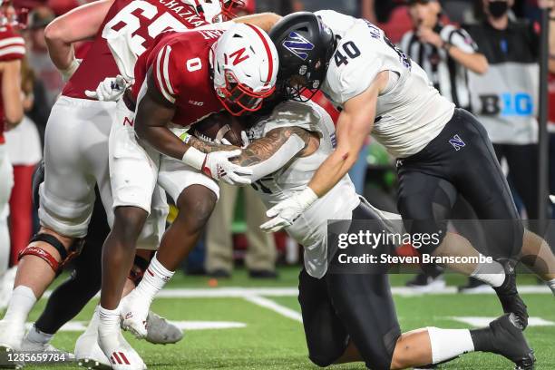 Linebacker Peter McIntyre and defensive lineman Samdup Miller of the Northwestern Wildcats tackle running back Jaquez Yant of the Nebraska...