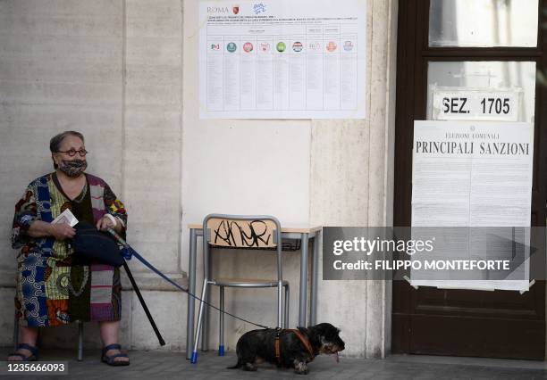 Woman with her dog waits to cast her vote at a polling station for the municipal elections in Rome on October 3, 2021. - Across the country, in...