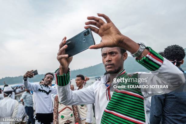 Man in traditional clothing takes a selfie during the celebration of Irreechaa, the Oromo people thanksgiving holiday, on the shore of a lake near...
