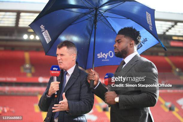 Sky Sports television pundits Roy Keane and Micah Richards stand pitchside underneath an umbrella during the Premier League match between Liverpool...