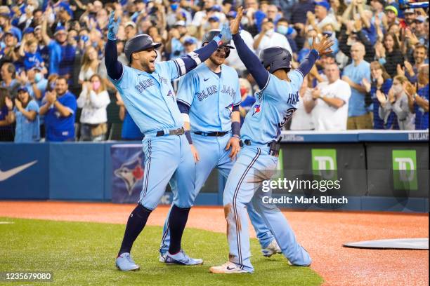 George Springer of the Toronto Blue Jays celebrates his grand slam with Teoscar Hernandez and Danny Jansen in the third inning during their MLB game...