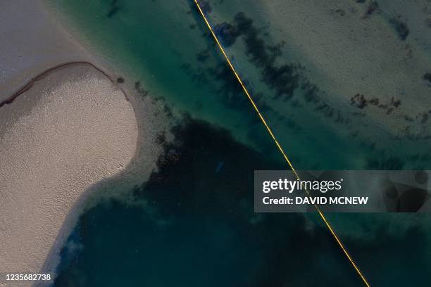 This aerial picture taken on October 3, 2021 shows oil and an oil containment boom in the water of the Talbert Marshlands area from an offshore oil...