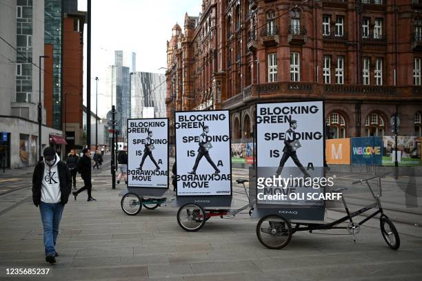 Pedestrians walk past Greenpeace posters outside the Manchester Central convention centre where the annual Conservative Party Conference is being...