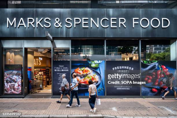 Pedestrians walk past the British multinational retailer Marks & Spencer food section store seen in Hong Kong.