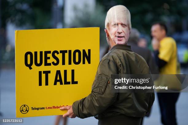 Protester, wearing a mask of British Prime Minister Boris Johnson, holds a sign reading "Question it all" on the final day of the Conservative Party...