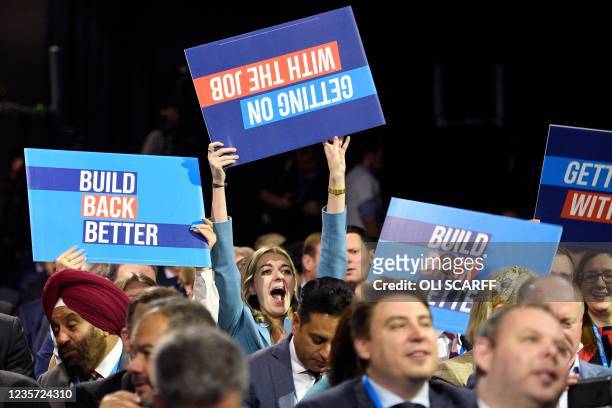 People raise placards as they wait for the keynote speech of Britain's prime minister at the Manchester Central convention centre on the final day of...