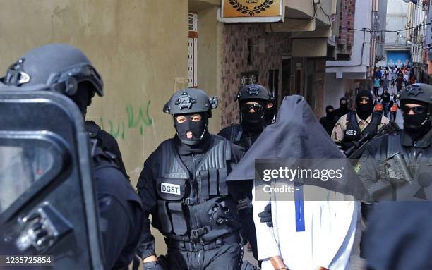 Members of Moroccos's Central Bureau of Judicial Investigation , which oversees counter-terrorism operations, escort a suspect outside a house in the...