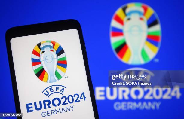 In this photo illustration, UEFA Euro 2024 logo is seen on a smartphone and a pc screen.