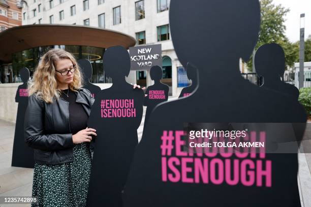 Campaigner poses with cut-out silhouettes representing women outside the Metropolitan Police headquarters New Scotland Yard in London on October 7,...