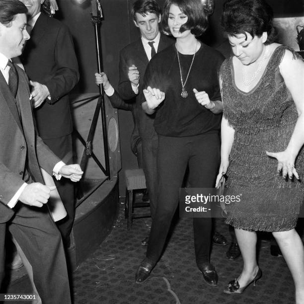 Picture taken on January 26, 1962 at Saint-Maurice, near Paris, showing Italian actress Sophia Loren C) dancing the "Twist" with French singer Regine...