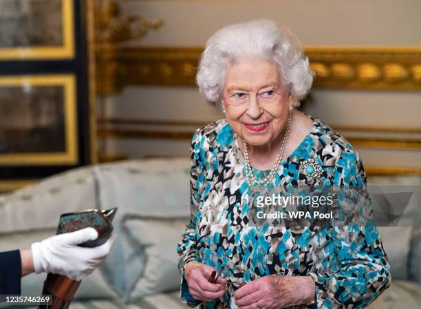 Queen Elizabeth II looks at the Birmingham 2022 Commonwealth Games Baton during the Baton Relay for Birmingham 2022, the XXII Commonwealth Games at...