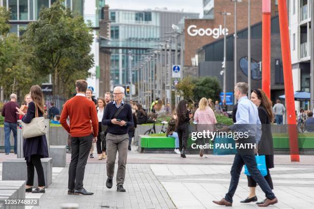 People take a lunch break in the business and financial sector of Dublin City centre with the Google offices in the background on October 7, 2021. -...