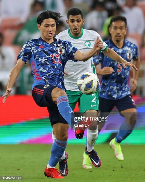 Japan's midfielder Takumi Minamino kicks the ball past Saudi's defender Sultan al-Ghanam during the 2022 Qatar World Cup Asian Qualifiers football...