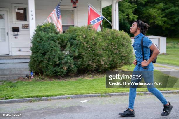 Travon Brown walks past a house on his street that hangs an American Flag and a Confederate Flag after organizing his second Black Lives Matters...