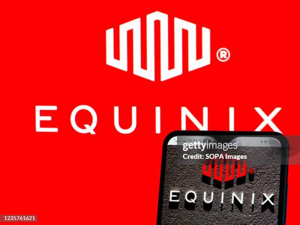 In this photo illustration, Equinix, Inc. Logo seen displayed on a smartphone and in the background.