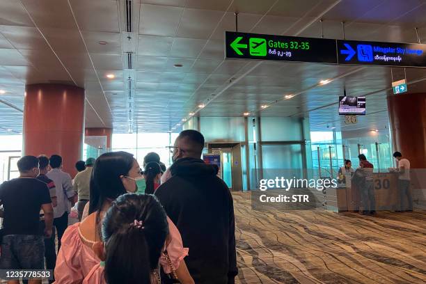 Travellers queue as they wait to board a flight from the airport in Yangon on October 9, 2021.