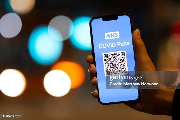 In this photo illustration a woman holds an Apple iPhone showing a NHS Covid Pass on October 8 in Cardiff, Wales. A covid pass for nightclubs and...