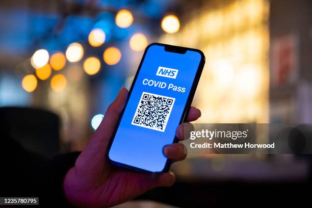 In this photo illustration a woman holds an Apple iPhone showing a NHS Covid Pass on October 8 in Cardiff, Wales. A covid pass for nightclubs and...