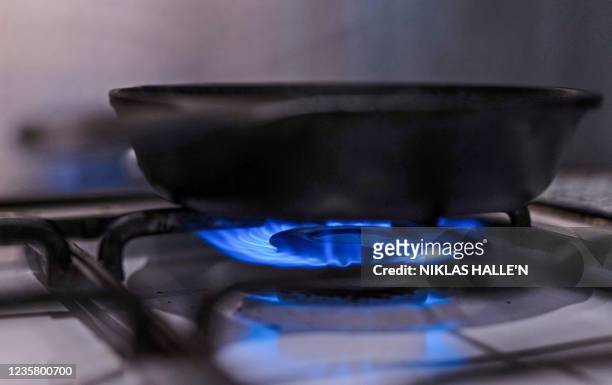 Photo illustration shows gas burning on a domestic hob in London on October 10, 2021. - European and UK gas prices surged to record peaks last week,...