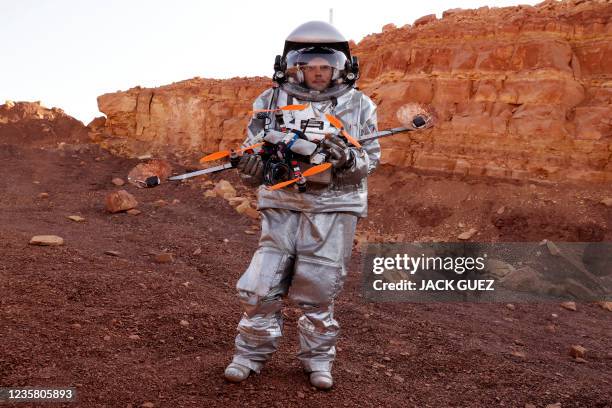 An astronaut from a team from Europe and Israel and dressed in a spacesuit holds a quadcopter drone during a training mission for planet Mars at a...