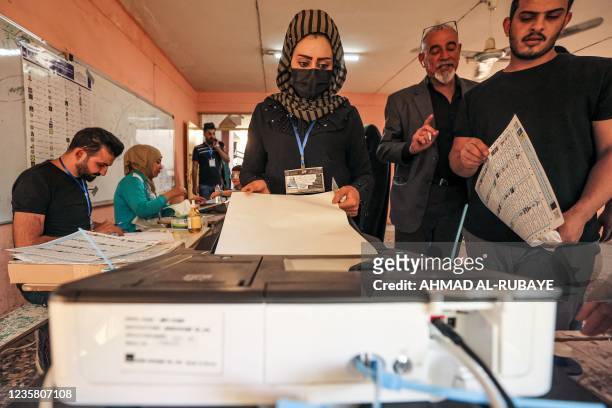 Woman voter casts her vote at a polling station in Iraq's capital Baghdad during the early parliamentary elections on October 10, 2021. - Iraqis on...