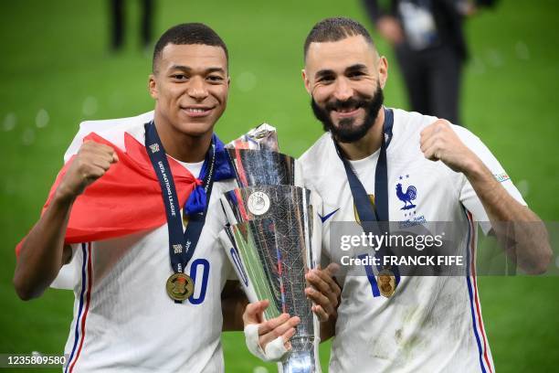 France's forward Kylian Mbappe and France's forward Karim Benzema celebrate with the trophy at the end of the Nations League final football match...