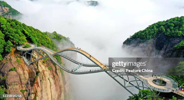 View of Ruyi Bridge, a bending glass-bottomed structure spanning across a canyon in Shenxianju scenic zone, in the clouds in Xianju county in east...