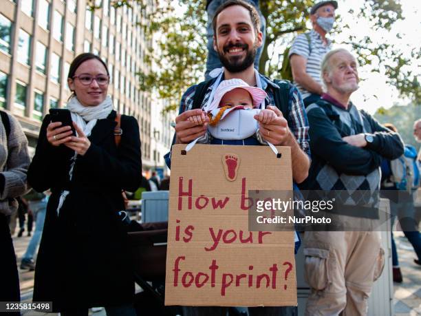 Man is holding his little born child and a placard in support of the planet, during the demonstration Back to Climate, organized in Brussels, on...
