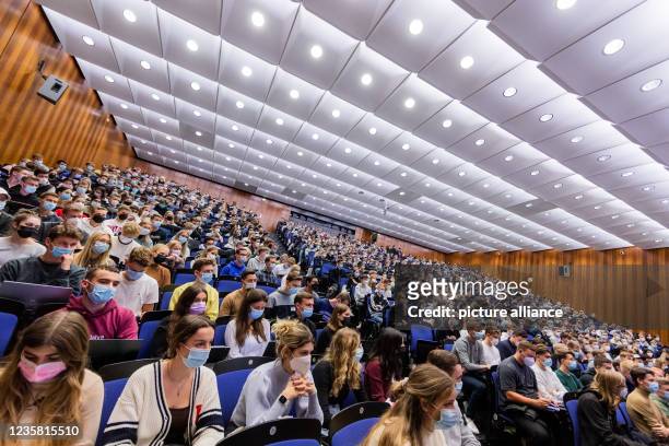 October 2021, North Rhine-Westphalia, Münster: Students wear mouth-to-nose coverings while sitting close to each other during the lecture "BWL 1" in...