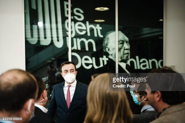 Christian Democratic Union Secretary General Paul Ziemiak speaks with journalists in front of a photo showing party co-founder and former chancellor...