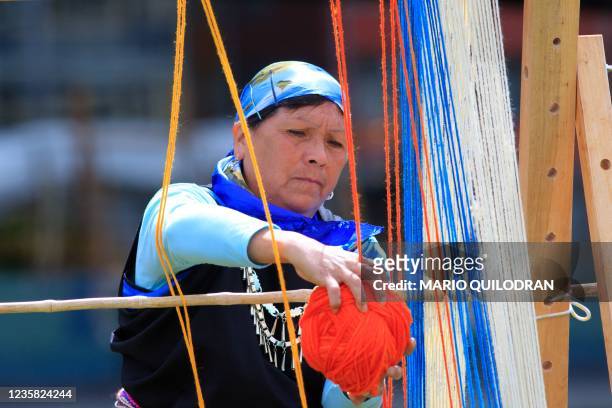 Chilean Mapuche woman weaves on a loom during a practice before trying to achieve a 1 kilometer weave in Temuco, Chile, on October 11, 2021. - Around...