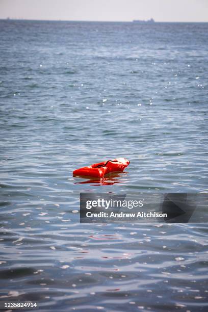 An orange life jacket that was used by an asylum seeker floating in the sea on the 8th of October 2021 in Folkestone, United Kingdom. The jacket fell...