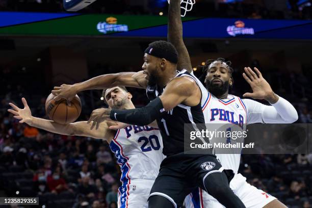 Bruce Brown of the Brooklyn Nets passes the ball against Georges Niang and Andre Drummond of the Philadelphia 76ers in the second half at the Wells...