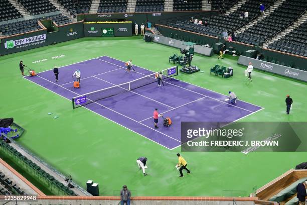 People dry the court in stadium 1 of Indian Wells during the rain delayed third round match between Coco Gauff of the US and Paula Badosa of Spain at...