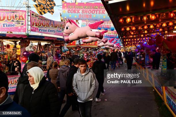 People walk past rides and stalls at the Hull Fair on October 11, 2021. - The Hull Fair, one of Europe's largest travelling fairs, returned after a...