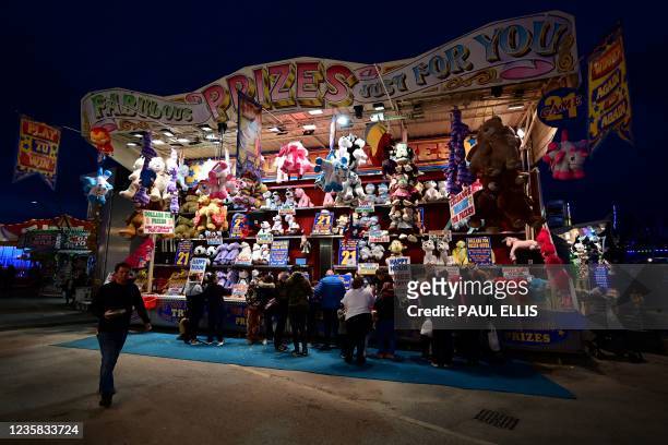 Visitors gather around a stall at the Hull Fair on October 11, 2021. - The Hull Fair, one of Europe's largest travelling fairs, returned after a...