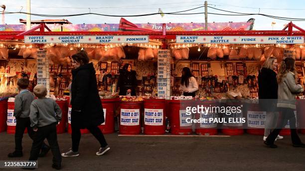 People walk past stalls at the Hull Fair on October 11, 2021. - The Hull Fair, one of Europe's largest travelling fairs, returned after a break due...