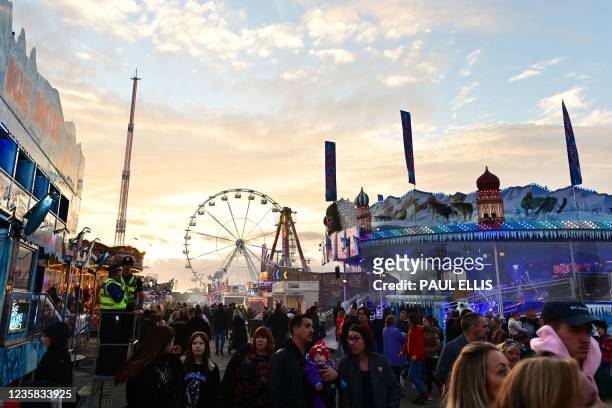 People walk past stalls and rides at the Hull Fair on October 11, 2021. - The Hull Fair, one of Europe's largest travelling fairs, returned after a...