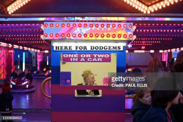 Woman waits for customers inside a booth at the Hull Fair on October 11, 2021. - The Hull Fair, one of Europe's largest travelling fairs, returned...