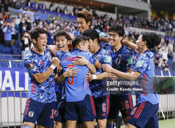 Japan's Ao Tanaka is congratulated by his teammates after opening the scoring during the first half of a Group B football match against Australia on...