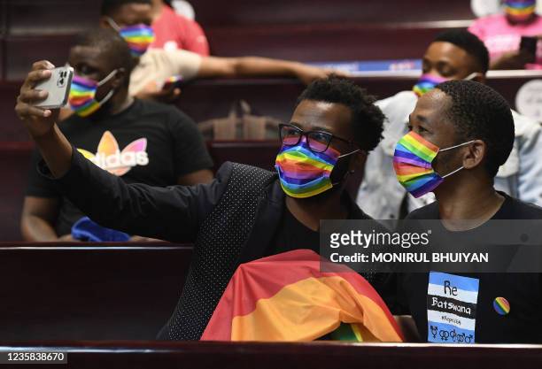 Activists wearing a rainbow mask take selfies at the Botswana High Court on October 12, 2021 where they gather to listen to the court proceeding as...