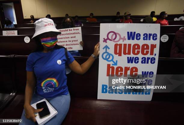 Activists wearing a rainbow mask sit at the Botswana High Court on October 12, 2021 place placards as they listen to the court proceeding as...