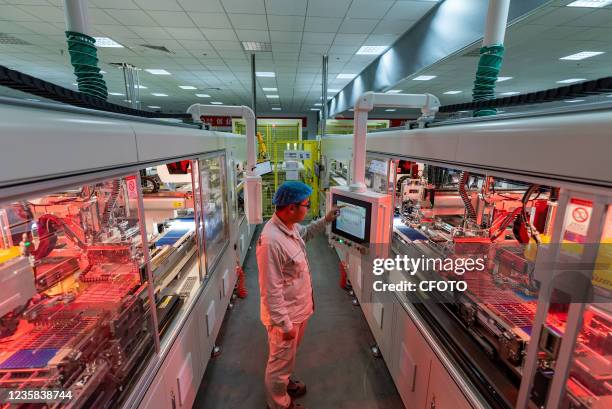 Worker operates an automatic series welding machine for battery strips at a GCL-CL-INTEGRATED high-efficiency photovoltaic module production workshop...