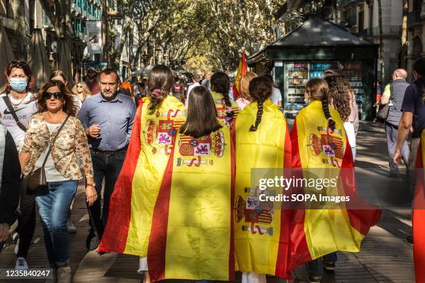 People are seen with Spanish flags on the Hispanic Day on the Rambla in Barcelona. People have attended the floral offering to the statue of...