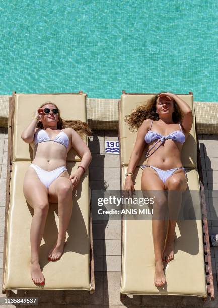 Tourists sunbathe by a swimming pool at a hotel in Tunisia's resort town of Hammamet, about 66 kilometres south of the capital Tunis, on October 7,...