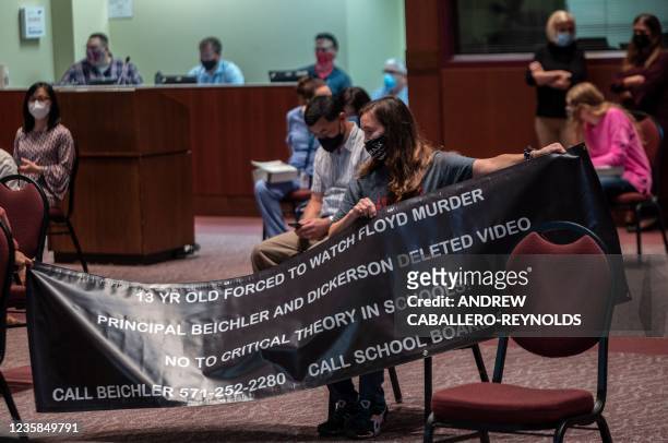 Woman holds up her sign against Critical Race Theory being taught during a Loudoun County Public Schools board meeting in Ashburn, Virginia on...
