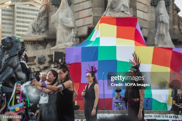 Protesters are seen in performance in front of the statue of Christopher Columbus with a Wiphala flag. Anti-colonial groups held a rally that marched...