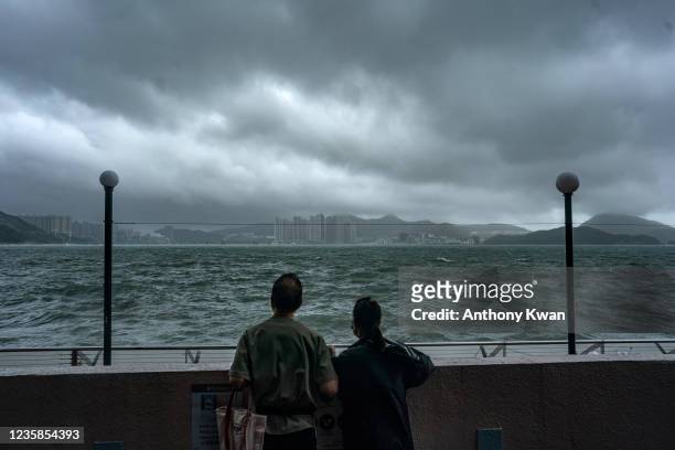 Couple stands in front of Victoria Harbour during a No. 8 Storm signal raised for Typhoon Kompasu on October 13, 2021 in Hong Kong, China. Hong Kong...