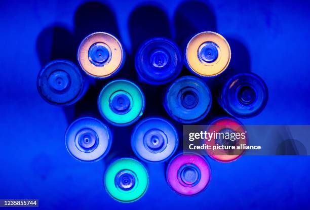 October 2021, Mecklenburg-Western Pomerania, Neubrandenburg: Empty spray bottles with neon colors stand under UV light in the future neon mini-golf...